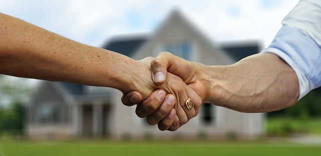 Homebuyer and Seller Shaking Hands in Front of the Home Sold